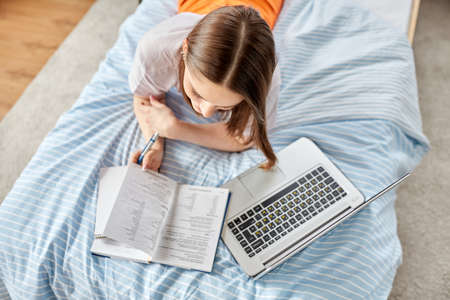 teenage student girl writing to notebook at home