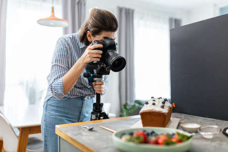 food photographer with camera working in kitchenの写真素材