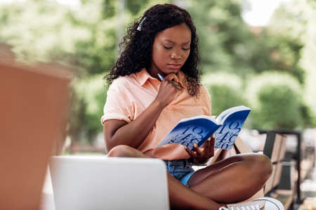 african student girl reading book in cityの写真素材