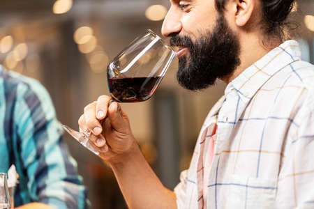 man with glass drinking red wine at restaurantの写真素材