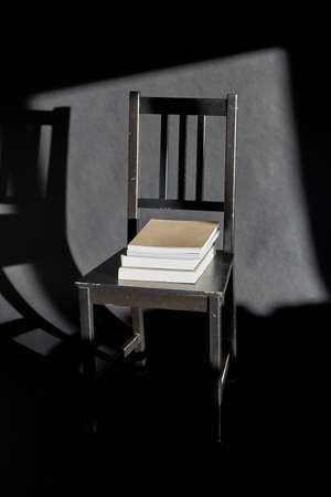 books on vintage chair on black background