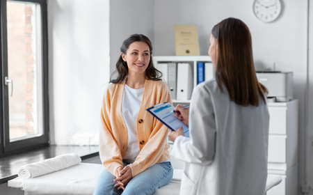 doctor with clipboard and woman at hospitalの写真素材