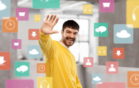 smiling young man in yellow sweatshirt waving hand