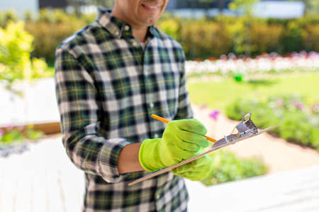 close up of man with clipboard at summer garden
