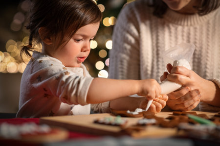 mother and daughter decorating gingerbread at homeの写真素材