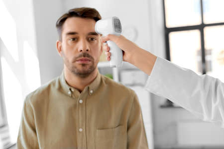 doctor with thermometer and man at hospitalの写真素材
