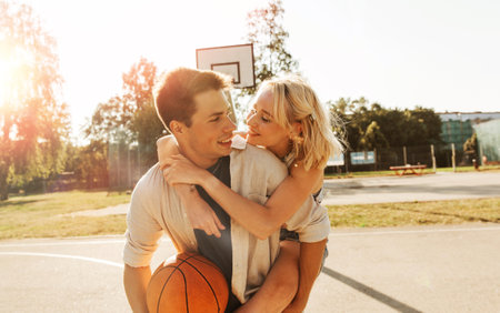 summer holidays, love and people concept - happy young couple with ball having fun on basketball playgroundの写真素材