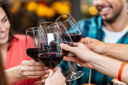 happy friends drinking red wine at restaurantの写真素材