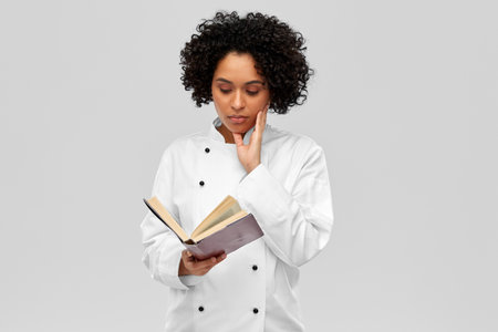 female chef in white jacket reading cook bookの写真素材