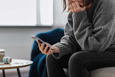 stressed woman with medicine and phone at home