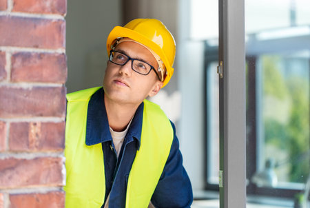 male builder in helmet looking out window