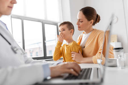mother, son and doctor with laptop at clinicの写真素材