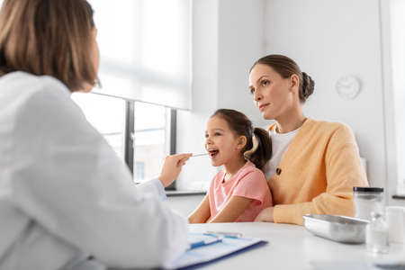 female doctor checking girls throat at clinicの写真素材