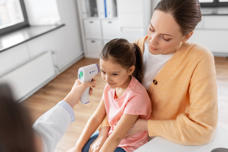 mother with sick daughter and doctor at clinicの写真素材
