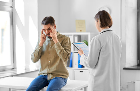 doctor and man with health problem at hospitalの写真素材