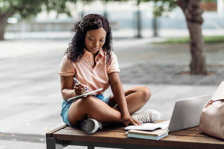 african student girl with laptop and books in cityの写真素材