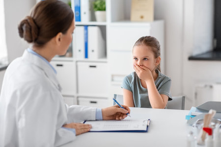 doctor and little girl patient coughing at clinicの写真素材