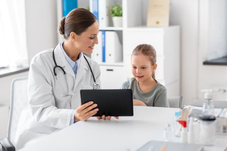 doctor showing tablet pc to little girl at clinicの写真素材