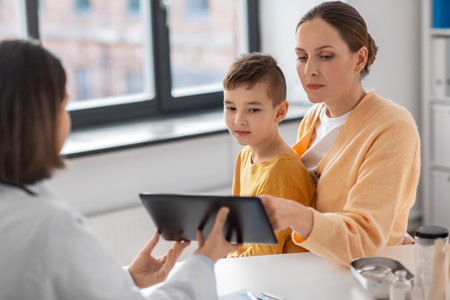 mother, son and doctor with tablet pc at clinicの写真素材