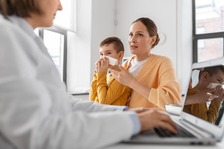 mother, son and doctor with laptop at clinicの写真素材