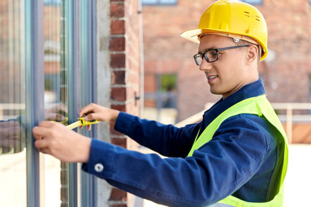 male builder with ruler measuring windowの写真素材