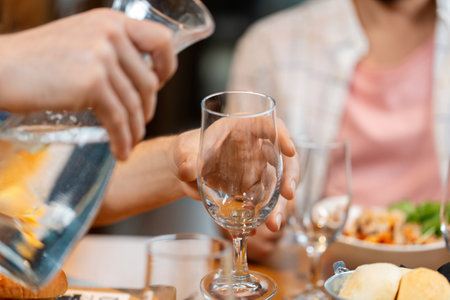 hands pouring water to glass at restaurantの写真素材