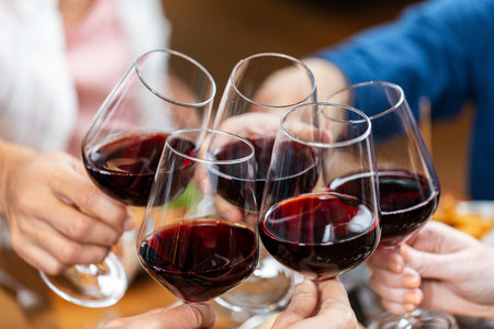 happy friends drinking red wine at restaurantの写真素材