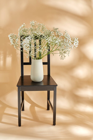 flowers in vase on chair over beige backgroundの写真素材