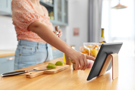 woman with tablet pc making cocktails at kitchenの写真素材
