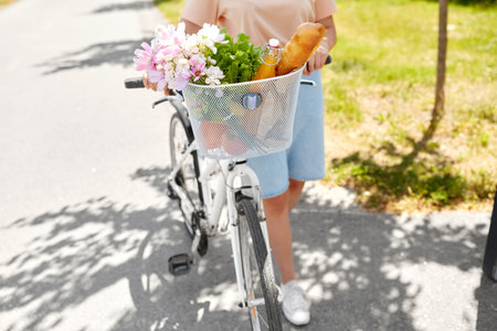 woman with food and flowers in bicycle basketの写真素材
