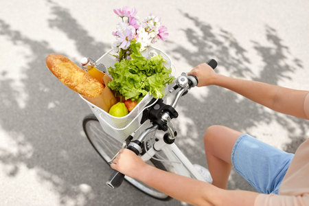 woman with food and flowers in bicycle basketの写真素材