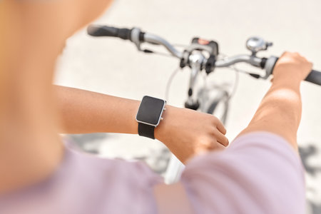 woman with smart watch riding bicycle in cityの写真素材