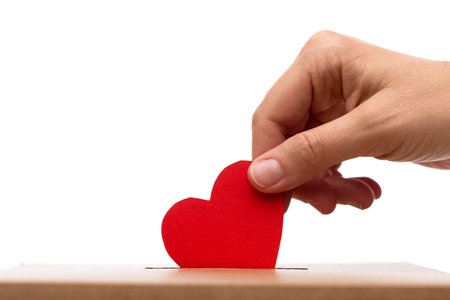 hand putting red heart into charity donation boxの写真素材