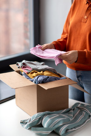 woman puts clothes in cardboard box for donationの写真素材