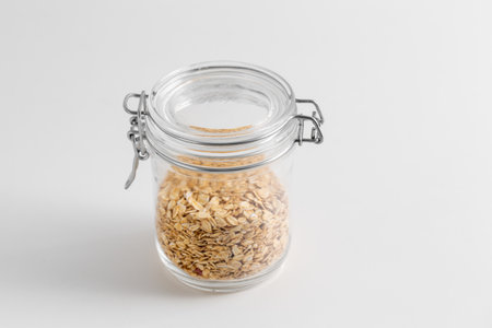 close up of jar with oat flakes on white tableの写真素材