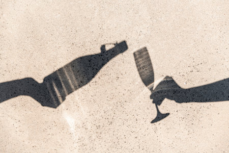 shadows of hands pouring wine to champagne glassの写真素材