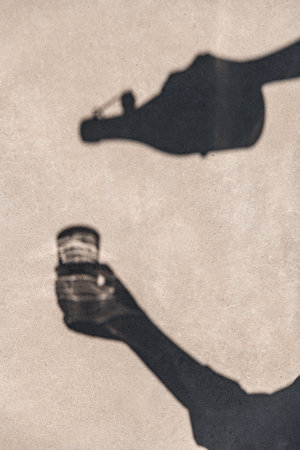 shadow of hands pouring drink from bottle to glassの写真素材