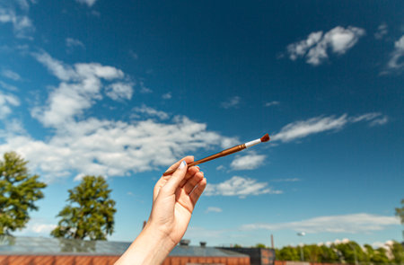 close up of hand with brush over blue skyの写真素材