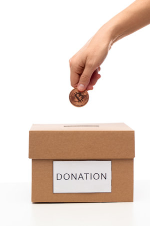 hand putting bitcoin into charity donation box