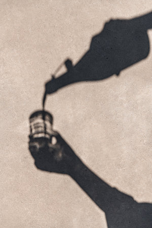 shadow of hands pouring drink from bottle to glassの写真素材