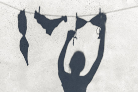shadow of woman hanging laundry on rope outdoorsの写真素材