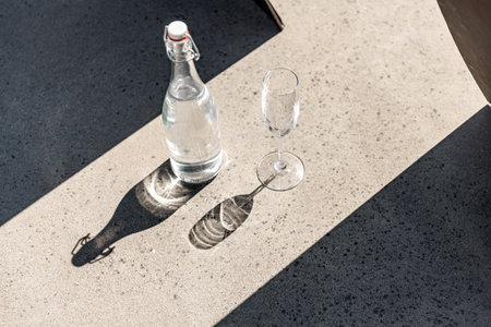bottle of water and glass on sunny floorの写真素材