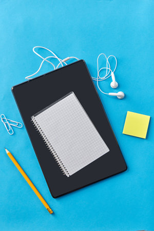 tablet pc , earphones, notebook and pencil on blueの写真素材