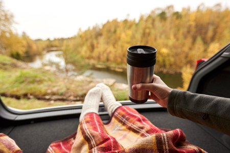 close up of woman holding thermo cup in car trunkの写真素材