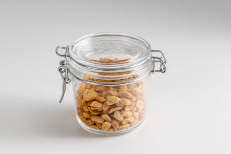 close up of jar with peanuts on white tableの写真素材
