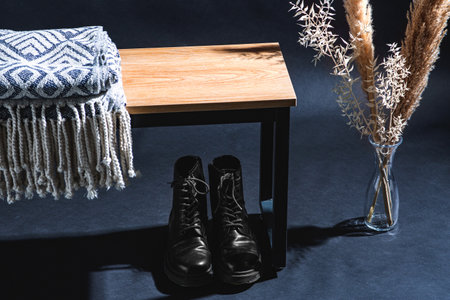 blanket on bench, boots and plants in dark roomの写真素材