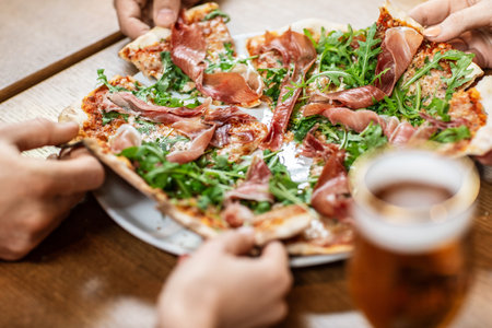 close up of friends eating pizza at restaurantの写真素材