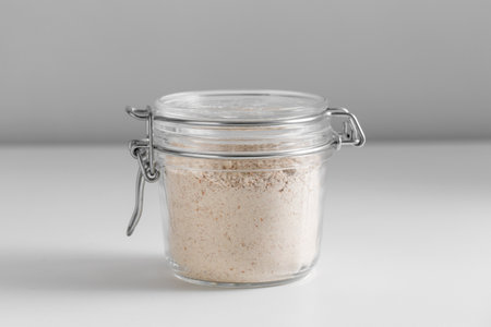 close up of jar with oat flour on white tableの写真素材