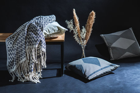 pillows and blanket on bench in dark roomの写真素材