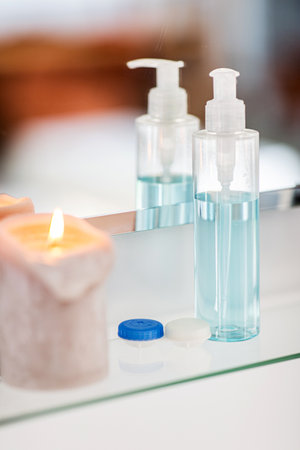 lotion, jars and candle on mirror in bathroomの写真素材